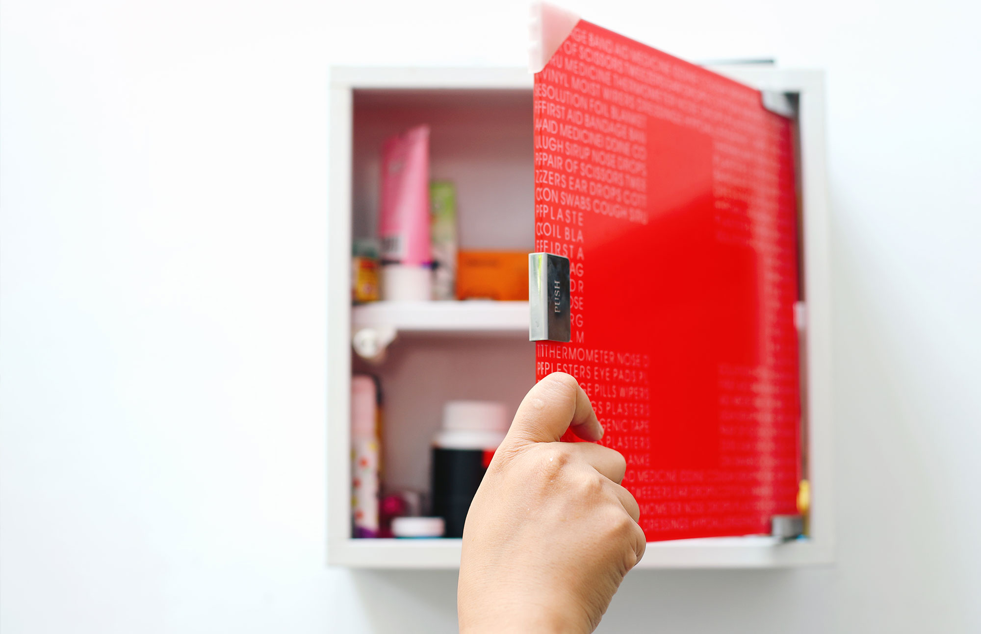 Hand öffnet roten Medizinschrank mit Arzneimitteln