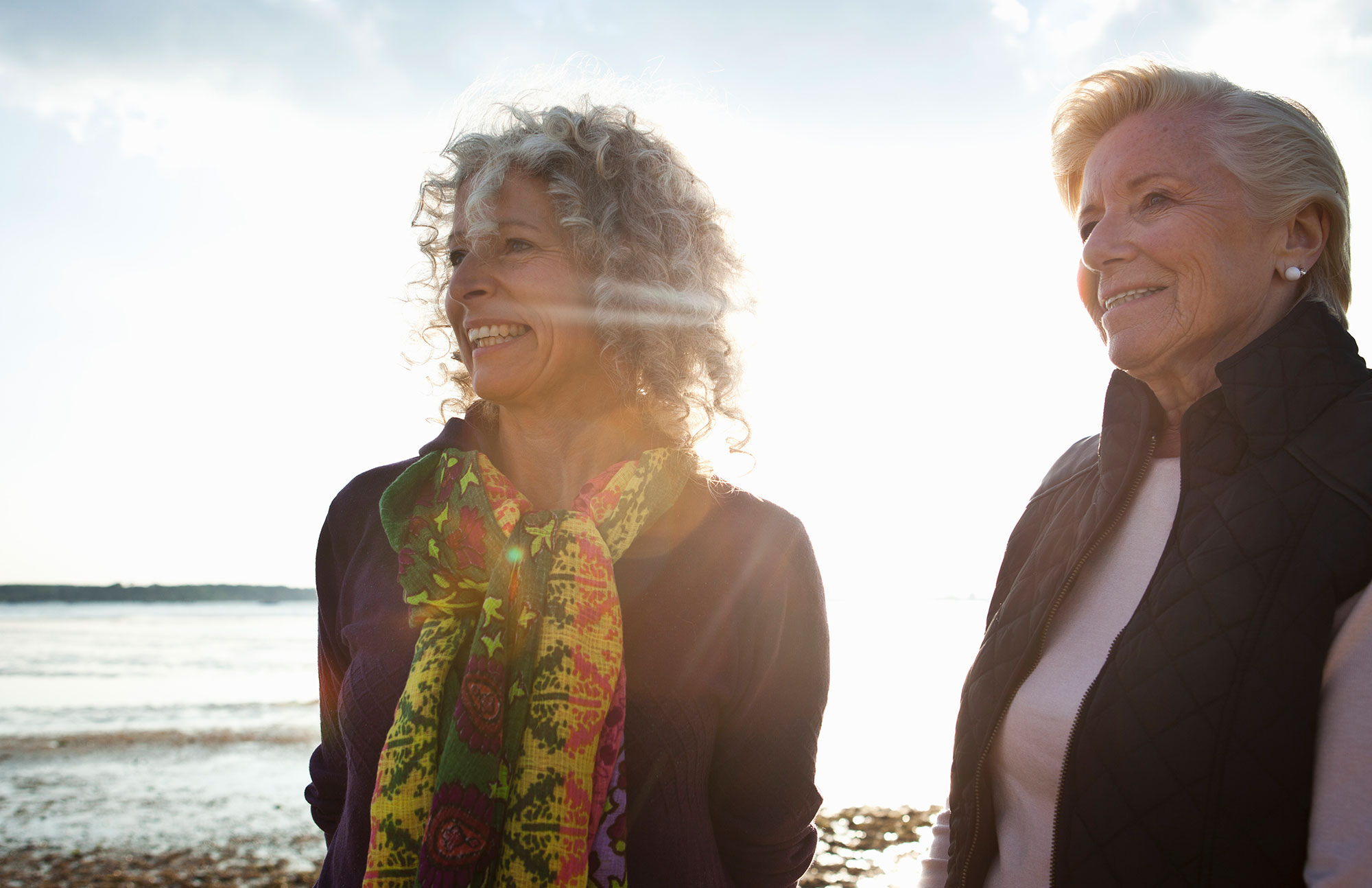 Zwei Frauen mittleren Alters stehen im Freien und lachen freundlich