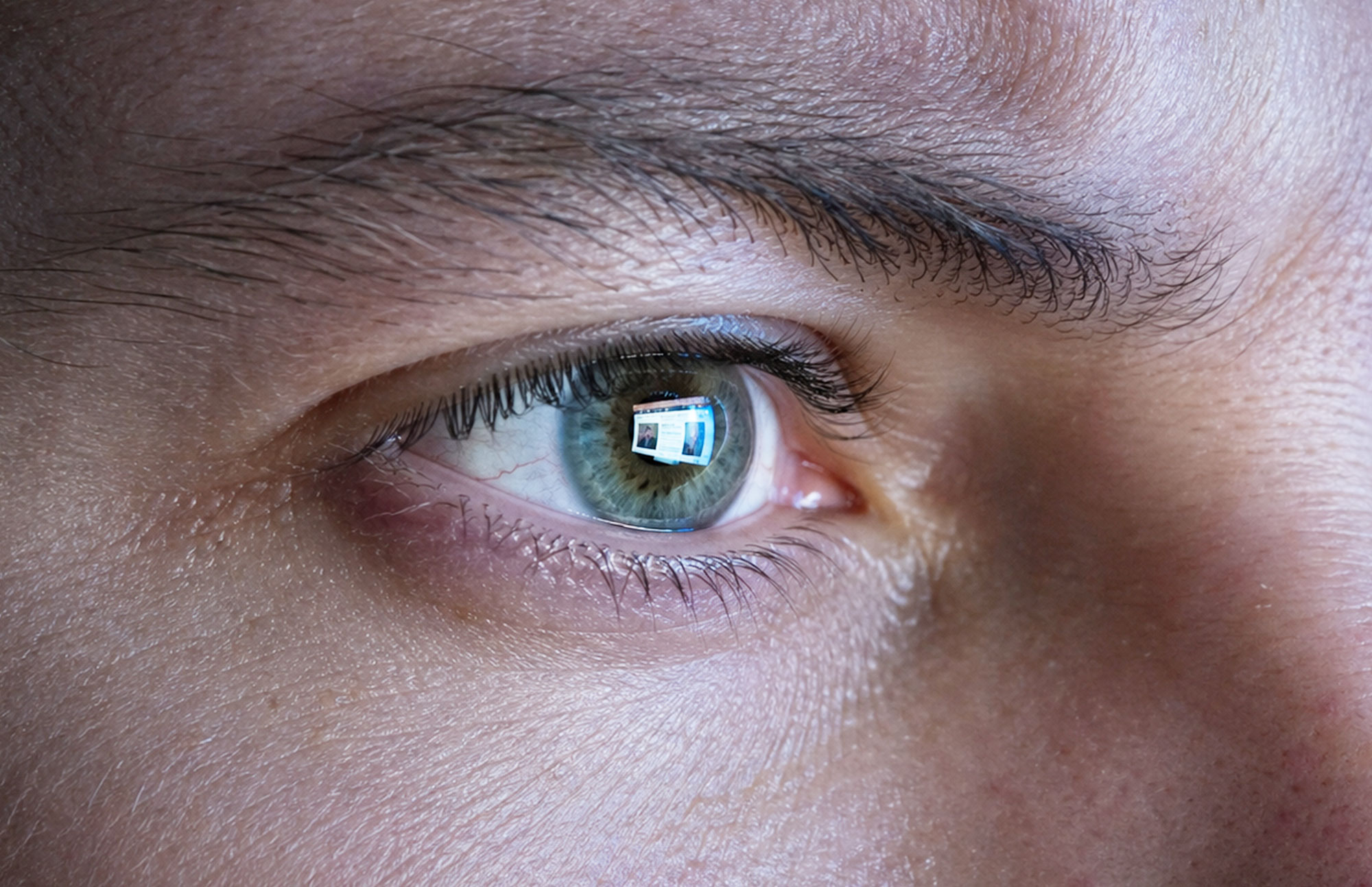 Detail eines menschlichen Auges mit sichtbarer Iris und Lichtreflexen